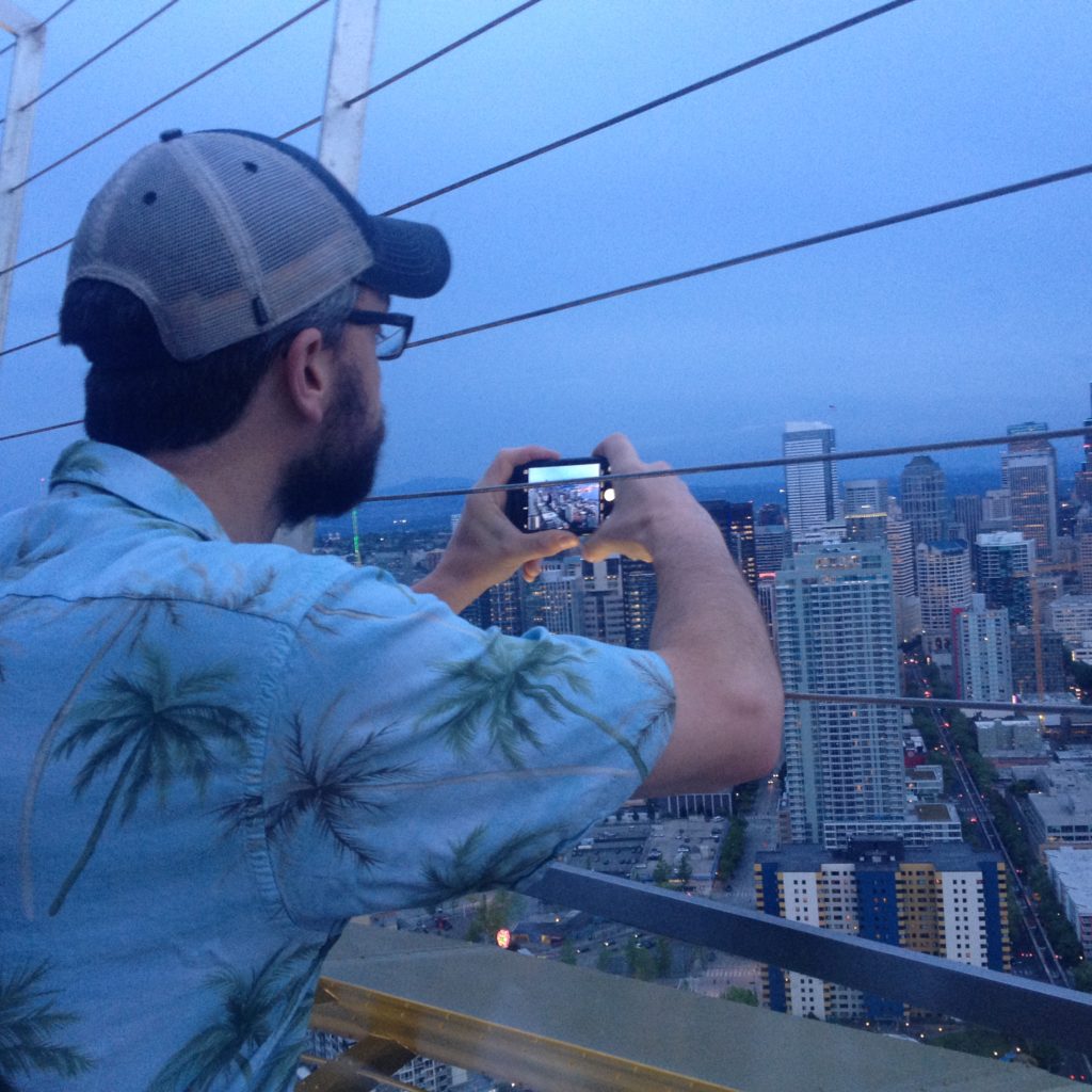 Rob on top of the Space Needle taking a picture of the Seatle Skyline